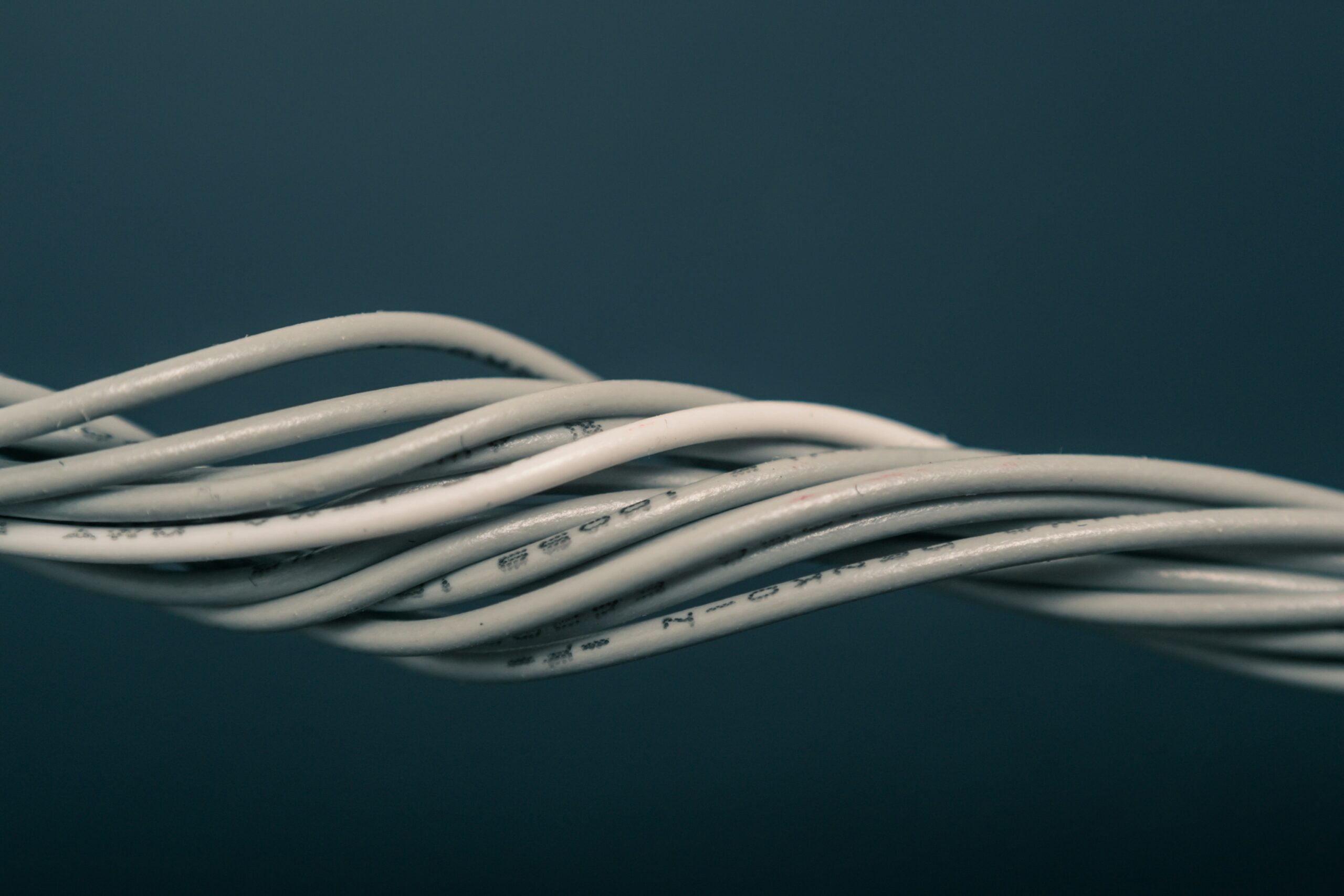 Close-up of twisted white electrical cables on dark background